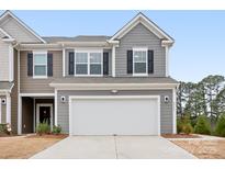 Two-story townhome with gray siding, white garage door, and landscaping at 2795 Yeager Nw Dr, Concord, NC 28027