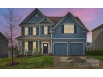 Two-story home with blue siding, two-car garage, and landscaping at 137 Yellow Birch Loop, Mooresville, NC 28117