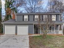 Two-story house with gray siding, white garage doors, and a covered porch at 4830 Carnbrook Pl, Charlotte, NC 28212