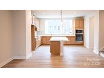 Bright kitchen features an island, wooden cabinets, stainless steel appliances and light wood floors at 7932 Cedarsmith Ct, Charlotte, NC 28217