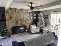 Cozy living room features a stone fireplace and hardwood floors at 8905 Vagabond Rd, Charlotte, NC 28227