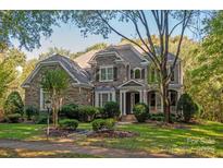 Two-story stone and shingle house with landscaped lawn and mature trees at 9042 Summer Club Rd, Charlotte, NC 28277