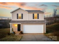 Two-story house with beige vinyl siding, a white garage door, and landscaping at 136 Jo Creek Ln, Harmony, NC 28634