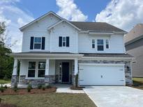 Charming two-story home featuring a white exterior, stone accents, a two-car garage, and professionally landscaped front yard at 4050 Caymen Bay Ct, Tega Cay, SC 29708