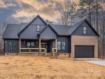 Modern farmhouse exterior boasts a dark gray metal roof and siding, contrasting brick accents, and a two-car garage at 2005 Plain Field Dr, Bessemer City, NC 28016