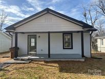 Newly renovated home featuring a white brick exterior, black trim, and a covered porch at 815 Jefferson St, Shelby, NC 28150