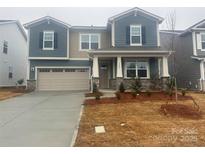 Two-story home features a two car garage, blue siding, stone accents and covered entryway at 1447 Honey Trl, Monroe, NC 28112