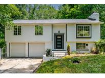Charming split-level home featuring a two-car garage and updated black trim windows, nestled in a lush, green setting at 6726 Wannamaker Ln, Charlotte, NC 28226