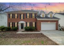 Charming two-story brick home featuring black shutters, a two-car garage, and a manicured lawn at 6654 Kingbird Ct, Charlotte, NC 28215