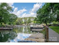Picturesque waterfront view featuring a dock, boat, and serene lake reflecting the clear blue sky at 1934 Hickory Hills Dr, Denver, NC 28037