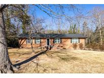 Charming brick home with a well-maintained lawn and mature trees on a sunny day at 206 Fox Den Rd, Troy, NC 27371