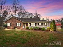 Brick ranch house with front porch and large yard at 7650 Tuckaseegee Rd, Kannapolis, NC 28081