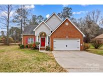 Charming brick home with a two-car garage, red door, and well-maintained front yard at 105 Whimbrel Ln, Mooresville, NC 28117