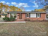 Charming red brick home featuring a well-maintained lawn and inviting front entrance and an attached carport at 2823 Edsel Pl, Charlotte, NC 28205