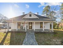 Inviting exterior showcasing a charming home with a covered front porch and stone pathway at 110 College St, Marshville, NC 28103