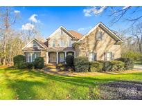 Charming two-story home with a stone and brick facade, mature landscaping, and a welcoming front porch at 3613 Savannah Way, Monroe, NC 28110