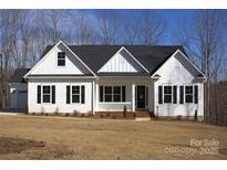 White farmhouse with black shutters, front porch, and attached garage at 131 High Lake Dr, Statesville, NC 28677