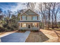 Two-story house with gray siding, dark brown accents, and a concrete driveway at 277 Stewart Nw St, Concord, NC 28027