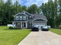 Two-story home with gray siding, two-car garage, and landscaped yard at 159 Charles Farm Dr, Cleveland, NC 27013