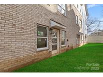 Tan three-story townhome with white garage doors and small grassy yard at 3709 Lou Ann Ave, Charlotte, NC 28208