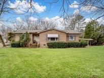 Brick ranch house with a well-manicured lawn and mature trees at 10140 Steele Creek Rd, Charlotte, NC 28273