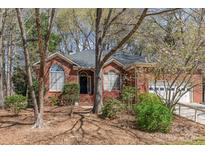 Charming brick home featuring arched windows, lush landscaping, and mature trees in a desirable neighborhood at 5550 Monticello Nw Dr, Concord, NC 28027