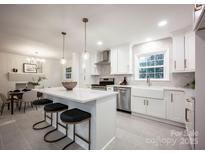 Bright kitchen features white cabinets, stainless appliances, and an island with bar seating at 7001 Starvalley Dr, Charlotte, NC 28210