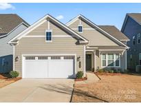 Tan two-story house with white garage door and landscaping at 1025 Lake Como Dr, Monroe, NC 28110