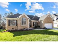 Brick house with a large front yard, attached garage, and well-manicured lawn at 3065 River Bend Dr, Tega Cay, SC 29708