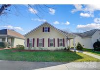 Charming yellow house with maroon shutters and a well-manicured lawn at 10117 Bishops Gate Blvd, Pineville, NC 28134