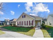 Charming yellow house with maroon shutters, welcoming porch, and manicured lawn at 10117 Bishops Gate Blvd, Pineville, NC 28134