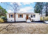 Charming white brick home featuring brown shutters, a wood door, and landscaped front yard at 5113 Grice Ct, Charlotte, NC 28210