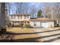 Two-story house with attached garage and driveway, nestled amongst trees at 6619 Wagon Oak Rd, Charlotte, NC 28212