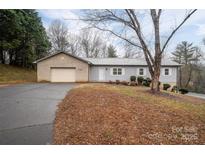 Ranch style home with gray siding, attached garage, and a tree in the front yard at 7704 Woodland Hills Rd, Hickory, NC 28602