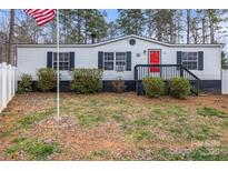 Charming single-story home with white siding, black shutters, a vibrant red door, and an American flag at 114 Catawba Woods Ct, Belmont, NC 28012