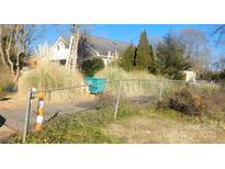 View of a house behind a chain link fence and overgrown grass at 123 E Branch Ave, Shelby, NC 28152