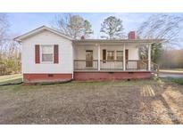 White house with red accents, covered porch, and grassy yard at 1028 White Ln, Gastonia, NC 28052