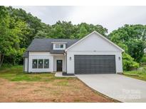 New construction featuring white siding, gray garage door, black trim, and professionally landscaped front yard at 117 Chavis Ln, Lincolnton, NC 28092