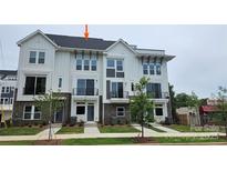 Beautiful three-story townhome with brick and Hardie board exterior, black railings, and professionally landscaped lawn at 1225 E 34Th St # Csw0419, Charlotte, NC 28205