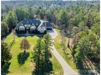 Expansive home featuring a long driveway and lush landscaping surrounded by a dense, mature forest at 9809 Saddle Ave, Waxhaw, NC 28173