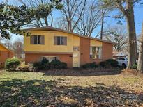 Charming front exterior featuring brick facade, mature trees, and a well-maintained lawn on a sunny day at 1608 Carfax Dr, Charlotte, NC 28216