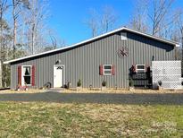 Gray metal barn-style home with red accents and landscaping; woodland setting at 1964 Nc Hwy 134 N Hwy # 4, Troy, NC 27371