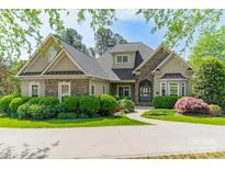 Charming home with stone accents, arched entryway, manicured lawn, and lush landscaping at 4150 Summit Ridge Ln, Denver, NC 28037
