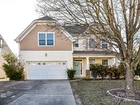 Two-story house with beige siding, white garage door, and landscaping at 9159 Marasol Ln, Concord, NC 28027
