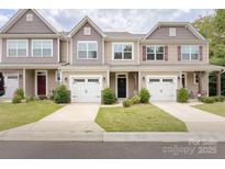 Tan three-unit townhome with white garage doors and landscaping at 11315 Savannah Creek Dr, Charlotte, NC 28273