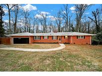 Brick ranch home with attached garage and landscaped yard at 8901 Douglas Dr, Charlotte, NC 28217