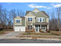 Two-story house with green siding, brick accents, and a three-car garage at 15725 Queens Trail Dr, Davidson, NC 28036