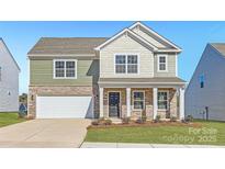 Two-story house with green and beige siding, stone accents, and a two-car garage at 1707 Wooten Way, Bessemer City, NC 28016
