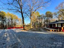 Ranch home with a gravel driveway, surrounded by trees and a large yard at 129 Hill Haven Rd, Statesville, NC 28677