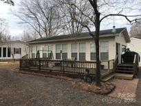 Cream-colored house with large windows, deck, and surrounding trees at 135/137 Indian Harbor Trl # E16/17, Mount Gilead, NC 27306